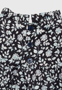 Musta kukkamekko, jossa on röyhelökaulus, vaaleansinisiä kukkakuoseja ja kolme tummansinistä nappia edessä.