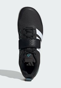 Black athletic shoe with a textured upper, featuring white stripes, a Velcro strap, and turquoise accents. Round toe and padded collar.