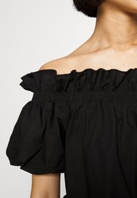 Schwarze schulterfreie Bluse mit rüschigem Ausschnitt, gerafftem elastischem Bund und Puffärmeln, aus glattem, leichtem Stoff gefertigt.