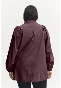 Maroon long-sleeve blouse with a high collar, puffed shoulders, and gathered cuffs. Made of lightweight fabric, featuring a pleat at the back.