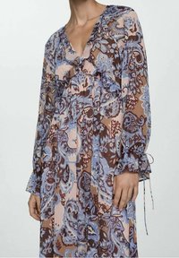 Dlouhá, volná šaty s paisley vzorem v odstínech modré, hnědé a růžové. Vyrobené z lehké tkaniny s volánovými akcenty a manžetovými stužkami.