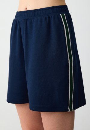 Navyblauwe sportshorts van een zachte stof, met contrasterende witte en groene zijstrepen en een elastische tailleband.