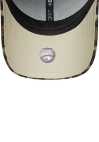 Gorra de béisbol con visera beige, forro interior negro, borde de camuflaje y una etiqueta holográfica de las Grandes Ligas de Béisbol en la visera.