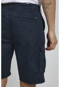 Marinblå cargoshorts i andningsbart material med flera fickor, knappdetalj och raka linjer.