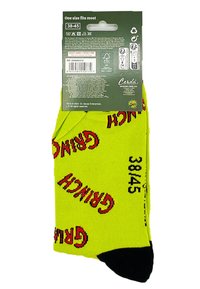 Calcetines amarillos con "GRINCH" impreso en rojo, talla 38-45, con puntera negra y textura acanalada. Incluye etiquetas de cuidado en el embalaje.