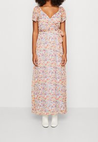 Abito lungo floreale con design avvolgente, caratterizzato da motivi arancioni, rosa e viola su uno sfondo azzurro chiaro, maniche a palloncino corte e vita con laccio.