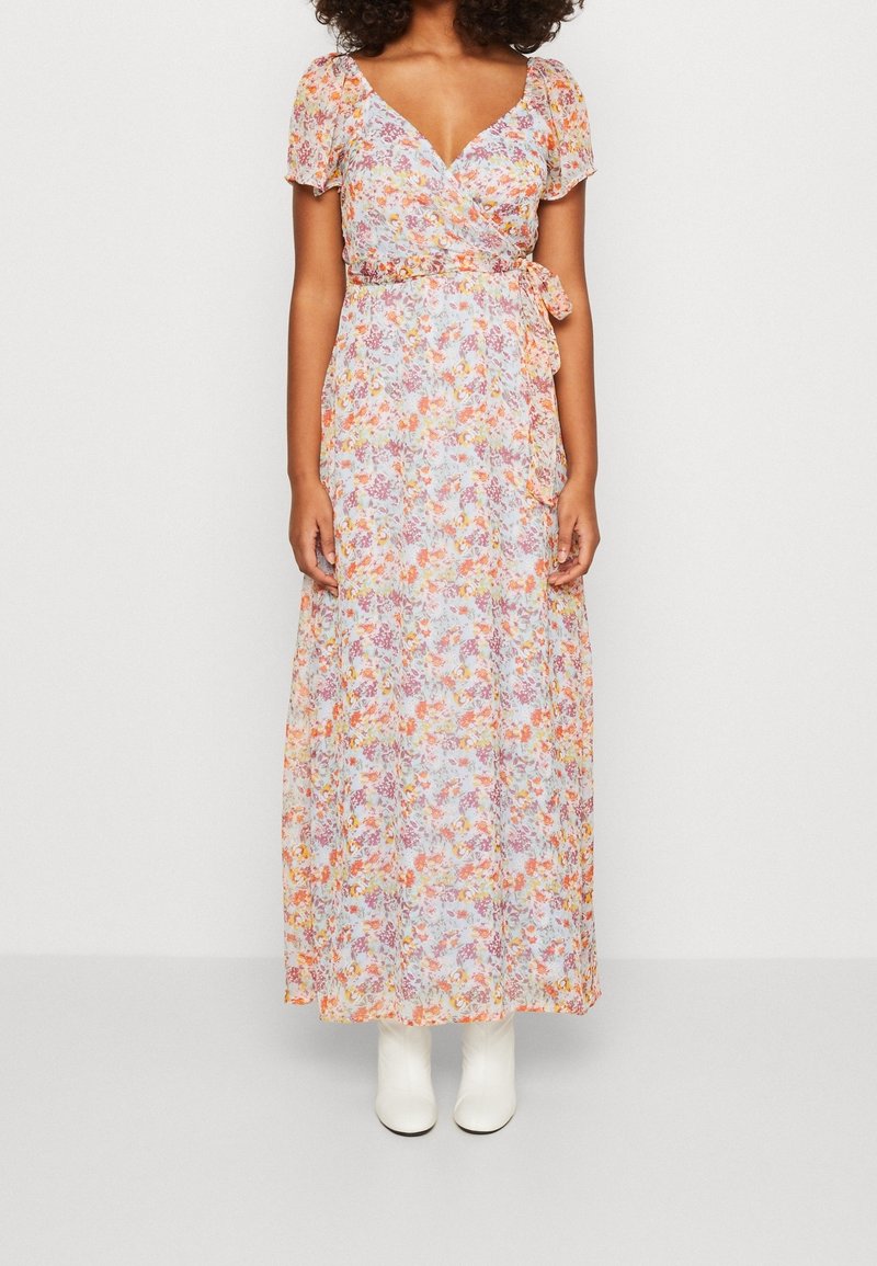 Abito lungo floreale con design avvolgente, caratterizzato da motivi arancioni, rosa e viola su uno sfondo azzurro chiaro, maniche a palloncino corte e vita con laccio.