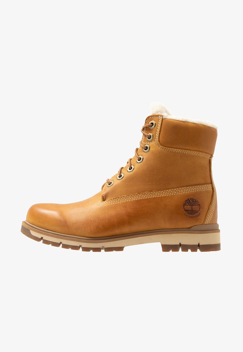 Braune Leder-Ankle-Boots mit einem weichen weißen Futter, Metallösen und einer gemusterten Gummisohle. Verfügt über ein Logo mit dem Text "WASSERDICHT".