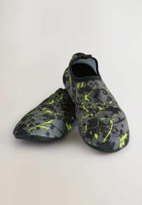 Szürke szövetcipők fekete és neon zöld pacás mintával. Slip-on dizájn, sima textúrával és lekerekített orral. Rugalmas talp.