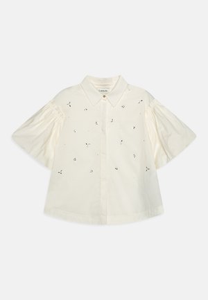 Biała bluzka z krótkim rękawem, z ostrym kołnierzykiem, bufkami i małymi rozproszonymi wzorami wycięć.