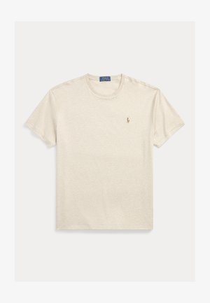 Beżowy bawełniany t-shirt z krótkim rękawem i okrągłym dekoltem, z małym wyszywanym logo na lewej piersi. Miękka tekstura, luźny krój.