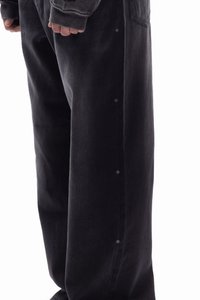 Svarte denimbukser med avslappet passform, med sidesømdesign med små kryssdetaljer, som fremhever en jevn tekstur og minimalistisk stil.