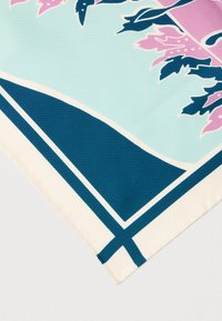 Μεταξωτό φουλάρι με γεωμετρικό σχέδιο σε μπλε και κρεμ αποχρώσεις και φυτικά στοιχεία σε ροζ και σκούρο πράσινο. Η υφή είναι ομαλή με τελειωμένο στρίφωμα.