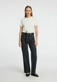 Vitt randigt t-shirt med korta ärmar, matchat med högmidjade svarta jeans. Svarta lägenheter fulländar looken med en minimalistisk design.