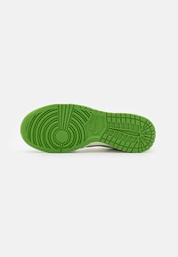 Nike shoe sole in vibrant green, featuring textured circular and linear patterns, with a logo embossed near the heel for traction and style.