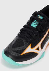 Black athletic shoe with mesh upper, orange and white accents, black laces, and a turquoise outsole. Features a streamlined design.