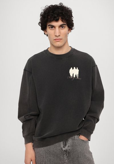 Mørkegrå hettegenser med rund hals, oversized passform og en kremfarget grafikk med tre silhuetter på brystet. Stoff i bomullsblanding.