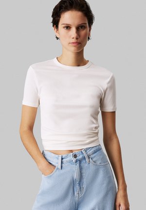 Kortærmet hvid ribbet t-shirt med rund hals, tætsiddende design, glat tekstur, parret med højtaljede lyseblå denimshorts.