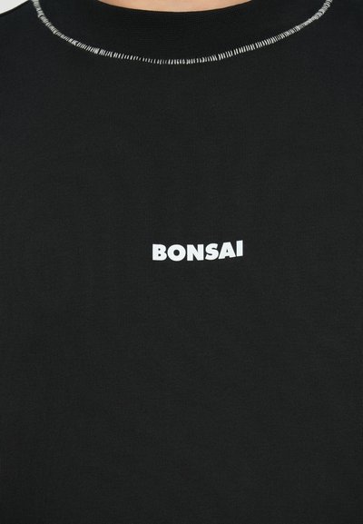 Czarna koszulka z bawełny o rypsowej strukturze. Posiada okrągły dekolt oraz biały nadruk "BONSAI" na przodzie.