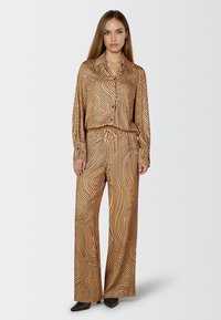 Brown patterned blouse with long sleeves, button closure, paired with wide-leg trousers featuring a similar design and elastic waistband.