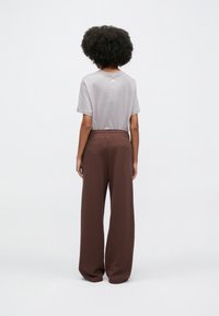 Γκρι κοντομάνικη μπλούζα με στρογγυλή λαιμόκοψη, συνδυασμένη με καφέ ανοιχτόσχεστη φόρμα με ελαστική μέση.