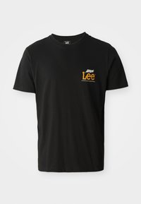 T-shirt noir en coton à manches courtes, col rond, avec un petit logo graphique orange et blanc sur la partie gauche de la poitrine.
