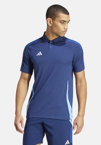 Navy blauwe polo met korte mouwen, gemaakt van vochtafvoerende stof. Voorzien van lichtblauwe zijstrepen en een logo met drie strepen.