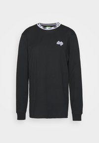 T-shirt preta de manga longa com um decote redondo em padrão xadrez e um pequeno logótipo branco no peito. Material de algodão suave, design ajustado.