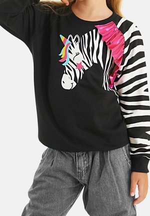 Sweat-shirt noir avec un motif zèbre et licorne, comprenant des accents colorés et un tissu rose froncé sur une manche. Détails rayés sur la manche.