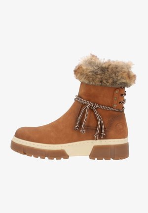 Bottine en daim marron avec col en fausse fourrure, lacets à motifs et semelle épaisse texturée. Présente des accents décoratifs en métal sur les côtés.