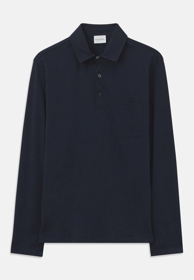 Tumesinise pika varrukaga polo-särk, mis on valmistatud pehmest kangast, klassikalise krae, kolme nupuga kinnituse ja rinnataskuga.