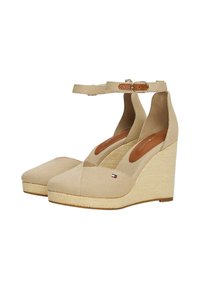 Beige Leinensandaletten mit Knöchelriemen, gewebtem Jute-Absatz, runder Zehenpartie und einem kleinen Logo-Detail an der Seite. Durchgehend glatte Textur.