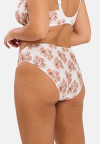 Culotte taille haute à motif floral en tissu blanc doux avec des fleurs roses et vertes. Présente une délicate dentelle le long de la taille.