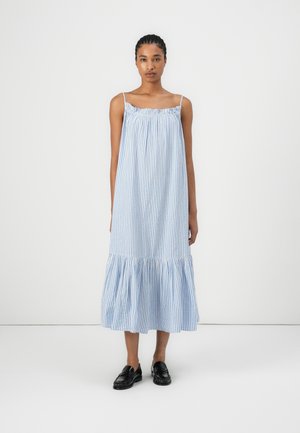 Abito senza maniche a righe blu e bianche con scollatura arricciata, orlo a strati con volant e tessuto leggero. Indossato con mocassini neri.