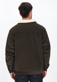 Barna corduroy dzseki krém színű műszőrme gallérral, hosszú ujjakkal és egyenes fazonnal. Két oldalsó zseb és gombdíszítés található rajta.