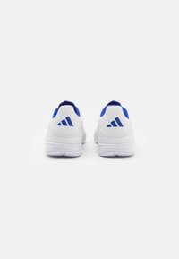 Zapatos deportivos blancos con acentos azules, que presentan una parte superior de malla texturizada, un collar acolchado y un prominente logo de tres franjas en el talón.