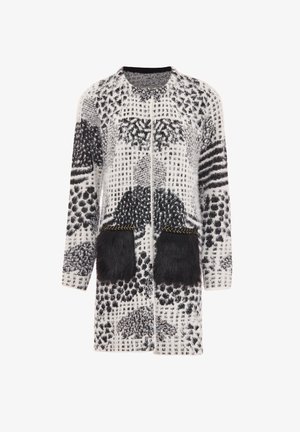 Strikket cardigan med sort og hvide mønstre, der har faux fur-lommer og guldsyninger, åben frontdesign og lange ærmer.