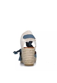Sandali a zeppa con tomaia in tela intrecciata bianca, dettagli in nastro blu e tacco avvolto in juta; la vista dal retro mette in evidenza il tacco texturizzato e le cinghie alla caviglia.