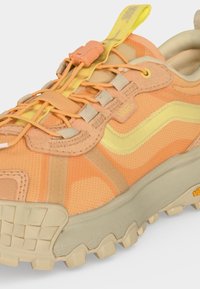 Baskets Vans orange et jaune avec semelle beige épaisse, lacets élastiques et languette de tirage sur fond blanc.