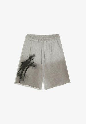 Shorts gris à taille élastique avec cordon de serrage et un motif abstrait en peinture aérosol noire sur la jambe gauche, avec des ourlets bruts.