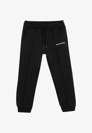 Pantalones de chándal negros con cinturilla ajustable, dos bolsillos laterales y el texto blanco "salva nuestras vidas" en la pierna izquierda. Tejido suave y puños acanalados.