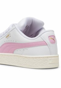 Fehér bőr sneaker rózsaszín velúr csíkkal, textúrált gumitalppal, és arany logó részlettel a nyelvén és a sarkán. Lekerekített orrforma.