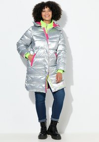 Doudoune argentée avec des accents rose vif, poches zippées et doublure intérieure vert fluo. Dotée d'une capuche et d'un détail textuel à l'ourlet.
