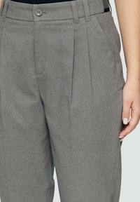 Graue Hose mit glatter Textur, die Falten, einen Knopfverschluss und Seitentaschen aufweist. Der taillierte Schnitt sorgt für eine strukturierte Passform.