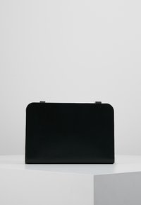Borsa a tracolla in pelle nera con una forma rettangolare strutturata, superficie liscia e design minimalista. Presenta dettagli in metallo dorato.