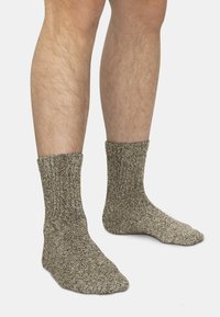 Texturierte graue Socken aus dickem Strickmaterial, mit einem gerippten Bündchen und einem etwas dunkleren Zehen- und Fersenbereich.