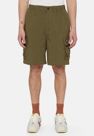Olive green cargo shorts with multiple pockets, elastic waistband, and contrasting stitching. Worn with white sneakers and brown socks.