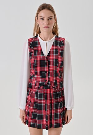 Completo in tessuto scozzese rosso e nero composto da gilet e gonna, abbinato a una camicia bianca a maniche lunghe. Include bottoni, pieghe e un colletto.