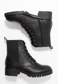 Bottines en cuir noir avec une finition texturée, à lacets sur le devant, fermeture éclair sur le côté et semelle en caoutchouc robuste avec un talon épais.