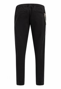 Pantalones jogger negros con cintura elástica, bolsillos traseros con cremallera y un acento de cadena plateada. Textura suave y diseño de pierna ajustada.